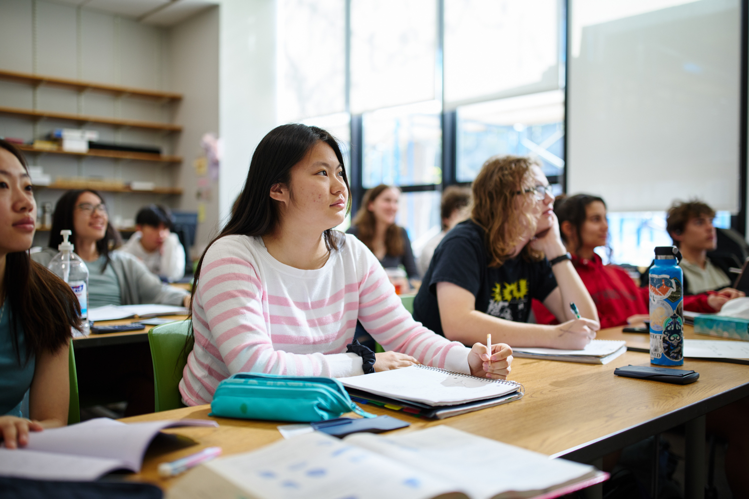 Student in a classroom smiling and looking at the board in front of them