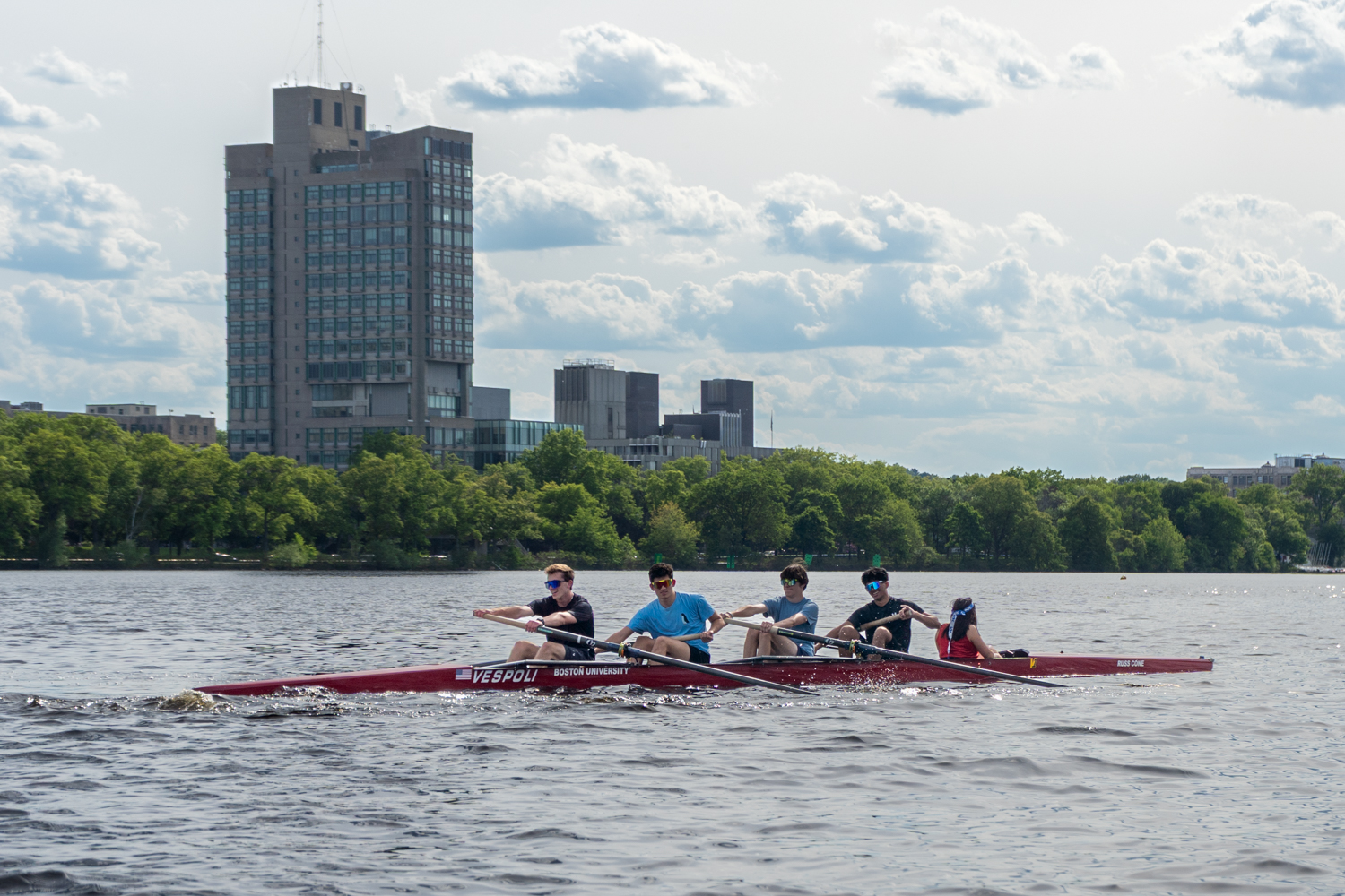 A crew boat of 5 students rowing on the Charles River near Boston University