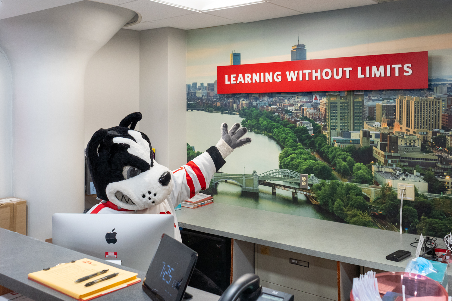 Rhett, the BU mascot, gesturing to a sign in the Boston University Building that says Learning Without Limits